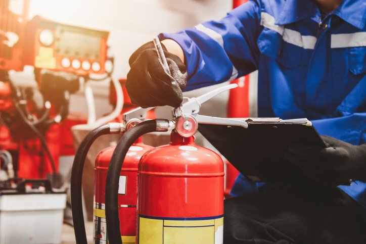 Bombeiro civil uniformizado verifica extintores de incêndio