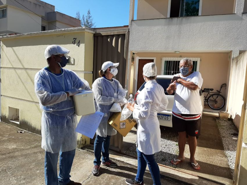 Agentes comunitários, de aventais e máscaras, fazem visitação domiciliar a homem também com máscara