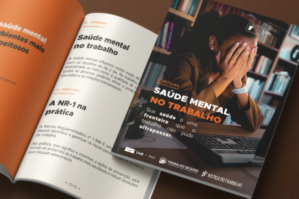 Foto de dois exemplares da cartilha Saúde Mental no Trabalho sobre mesa.