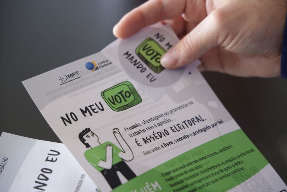 pessoa segura cartaz e adesivo da campanha - no meu voto mando eu