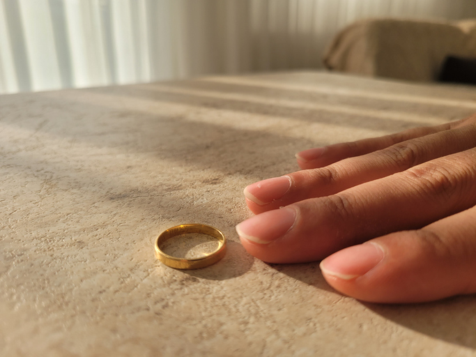 Mão de mulher com aliança dourada sobre uma mesa