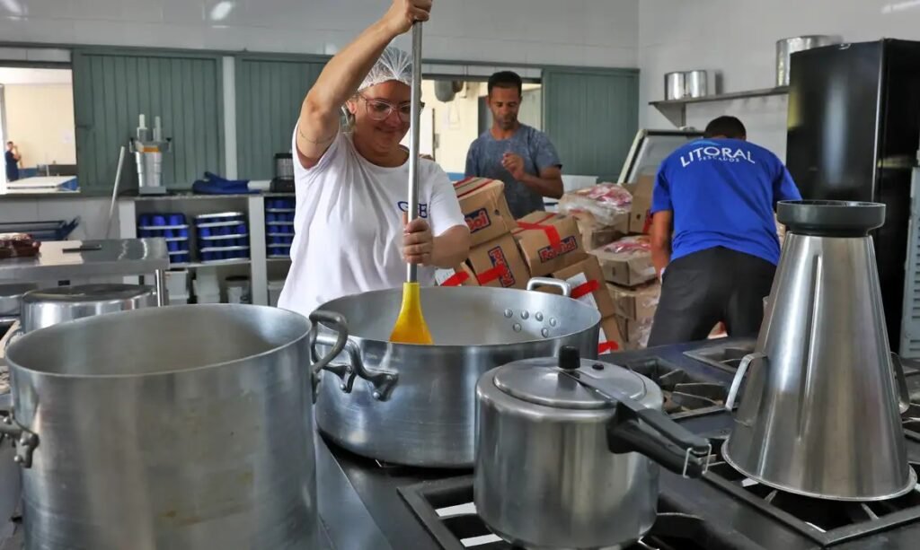 Merendeira preparando comida em cozinha escolar