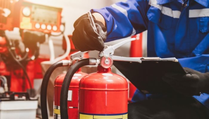 Bombeiro civil uniformizado verifica extintores de incêndio