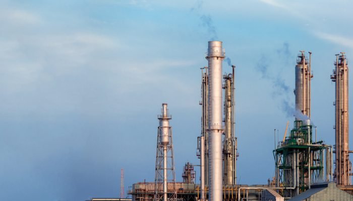 Torres metálicas de indústria química soltando fumaça no ar