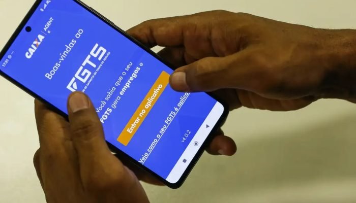 Mãos de homem negro olhando, mexendo em aplicativo do fgts