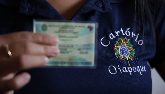 pessoa segura documento de identificação e usa camisa com a inscrição - cartório oiapoque