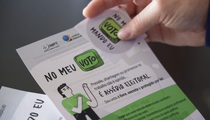 pessoa segura cartaz e adesivo da campanha - no meu voto mando eu