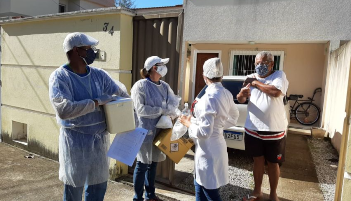 Agentes comunitários, de aventais e máscaras, fazem visitação domiciliar a homem também com máscara