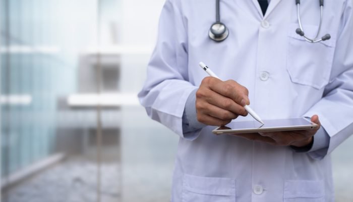 Médico fazendo anotações em tablet