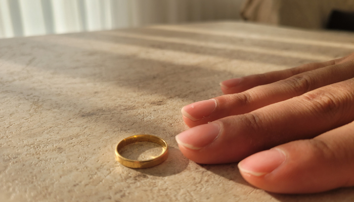 Mão de mulher com aliança dourada sobre uma mesa