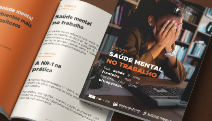 Foto de dois exemplares da cartilha Saúde Mental no Trabalho sobre mesa.