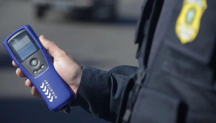 Policial todoviário segurando equipamento de teste do bafômetro
