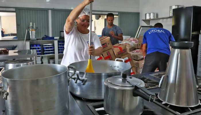 Merendeira preparando comida em cozinha escolar